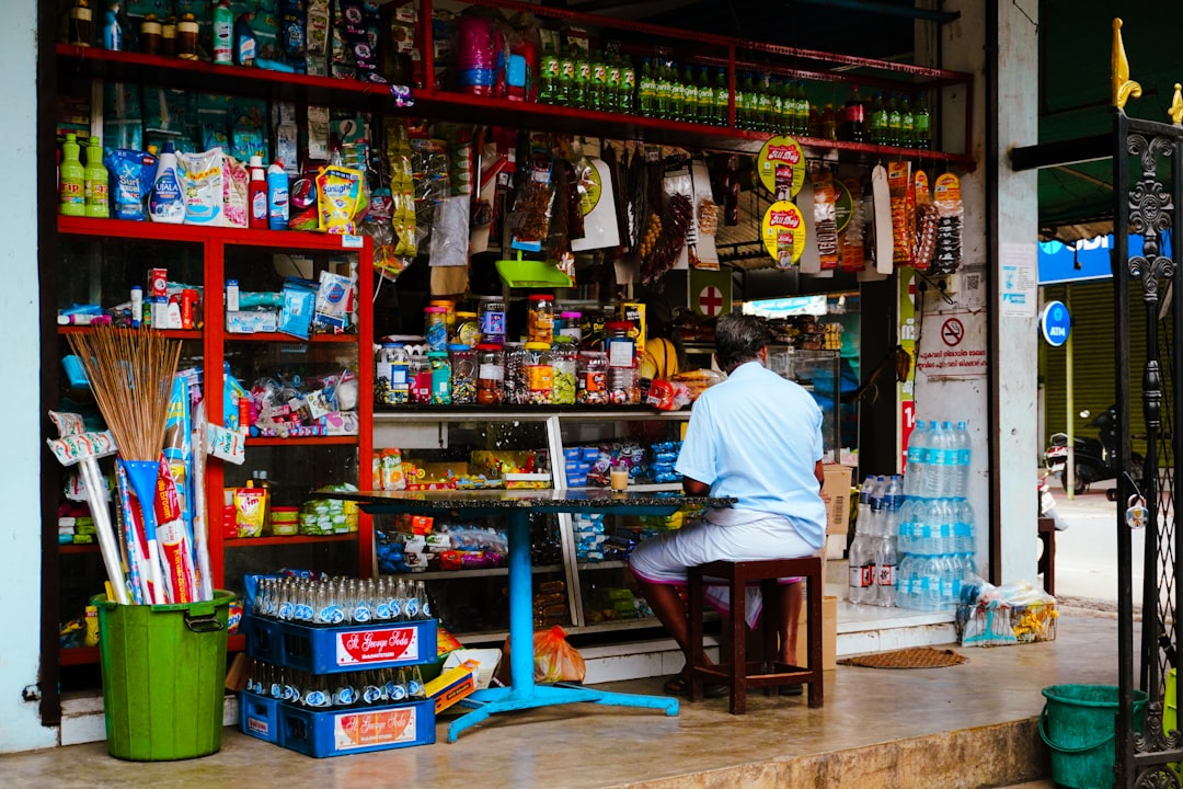 services-04 man-sits-at-a-small-table-outside-a-well-stocked-store-ltesgl96v0e